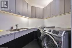 Utility room featuring ample cabinetry, a double basin sink, and integrated under-cabinet lighting - 