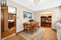 Dining area featuring tile flooring, a semi-flush mount ceiling light, and an open doorway to a separate room with wood-finish flooring and built-in shelving - 