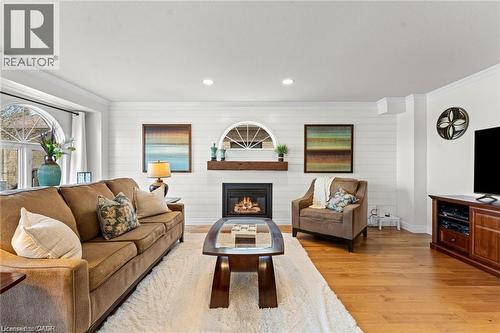 Living area featuring wood-finish flooring, a contemporary fireplace with a rustic wood mantel, and white shiplap accent wall - 26 Shadyridge Place, Kitchener, ON 