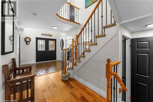 Two-story foyer featuring hardwood flooring, a contrasting tile entry, double doors with decorative glass inserts, a carpeted staircase with wood handrails and wrought iron balusters, and a second-sto - 26 Shadyridge Place, Kitchener, ON 
