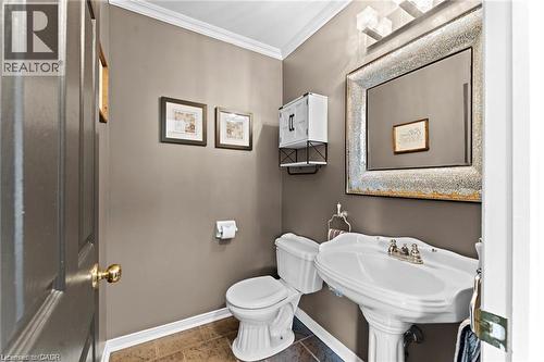 Pedestal sink with chrome fixtures, complemented by a large framed mirror and wall-mounted light fixture - 26 Shadyridge Place, Kitchener, ON 