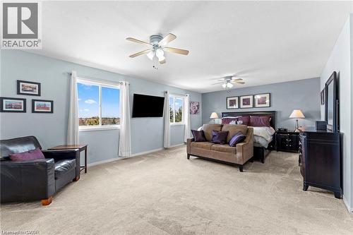 Spacious room with light neutral carpeting, multiple windows providing natural light, and two ceiling fans - 26 Shadyridge Place, Kitchener, ON 