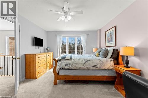 Carpeted bedroom with a large window, a ceiling fan, and a wall-mounted television - 26 Shadyridge Place, Kitchener, ON 