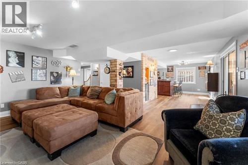 Spacious lower-level entertainment area featuring wood-finish flooring, recessed lighting, track lighting, and a built-in bar with brick-style accents - 26 Shadyridge Place, Kitchener, ON 