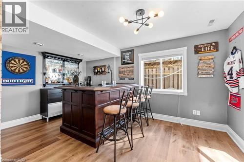 Built-in dark wood bar with seating for four, featuring an integrated glass rack and adjacent cabinetry - 26 Shadyridge Place, Kitchener, ON 