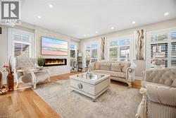 Spacious living area featuring hardwood flooring, recessed lighting, and multiple windows with plantation shutters - 