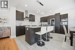 Gourmet kitchen featuring dark wood-finish cabinetry, stainless steel appliances, a center island with bar seating, granite countertops, and a decorative tile backsplash - 