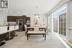 Open-concept kitchen and dining area featuring light-toned tile flooring - 