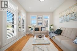 Living area featuring wood-finish flooring, recessed lighting, and multiple windows with white plantation shutters - 