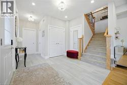 Foyer entry featuring plank-style tile flooring, recessed lighting, and a staircase with natural wood handrails and carpeted treads - 