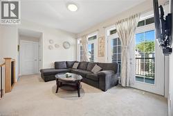Bright living area with three sets of French doors, an integrated wall-mounted television bracket, and light-toned carpeting - 