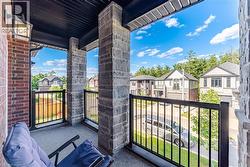 Balcony featuring brick exterior, stone pillars, black metal railings, and a concrete floor - 