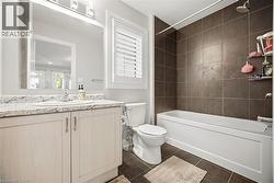 Bathroom featuring a single vanity with stone-look countertop, integrated sink, and light-toned cabinetry - 