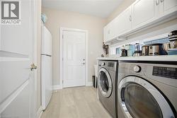 Dedicated laundry area featuring a white countertop, upper cabinetry, and tile flooring - 