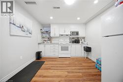 Kitchen featuring wood-finish flooring and white cabinetry - 