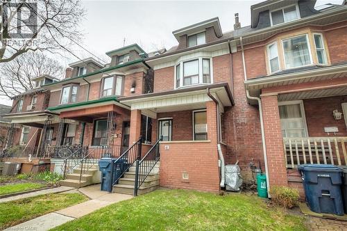Brick townhouse exterior featuring a covered porch with black metal railings, bay window, and dormer windows - 41 Springhurst Avenue, Toronto, ON 
