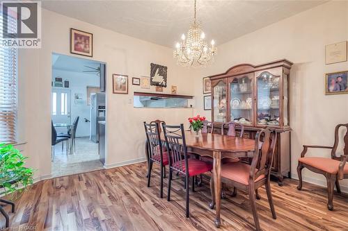 Dining area featuring wood-finish flooring, a crystal chandelier, and a pass-through window to the adjacent kitchen - 41 Springhurst Avenue, Toronto, ON 