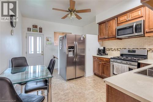 Kitchen featuring wood cabinetry, stainless steel appliances, a tile backsplash, and light-toned countertops - 41 Springhurst Avenue, Toronto, ON 