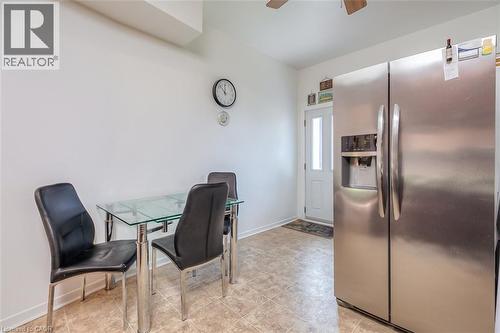 Kitchenette featuring neutral wall paint, light-toned tile flooring, a built-in stainless steel refrigerator with an ice and water dispenser, and a white paneled exterior door with a frosted glass ins - 41 Springhurst Avenue, Toronto, ON 