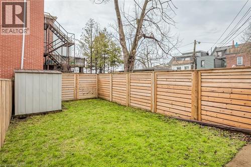 Enclosed backyard featuring horizontal-slat wood fencing, a verdant lawn, and a storage shed - 41 Springhurst Avenue, Toronto, ON 