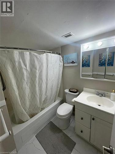 White vanity with chrome fixtures and integrated sink, alongside a white toilet and a bathtub with shower - 225 Harvard Place Unit# 1505, Waterloo, ON 