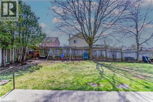 Expansive grassy yard featuring mature trees and a wooden privacy fence - 27 Tassie Lane, Cambridge, ON 