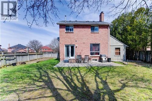 Brick exterior with a large patio area, double-door access, upper-level windows, a prominent chimney, and a fenced perimeter - 27 Tassie Lane, Cambridge, ON 
