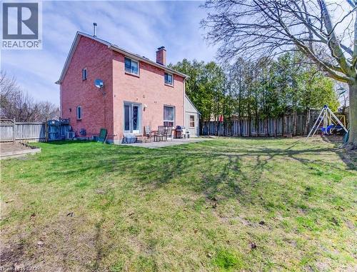 Expansive backyard featuring a manicured lawn, a large mature tree, and a wooden privacy fence - 27 Tassie Lane, Cambridge, ON 