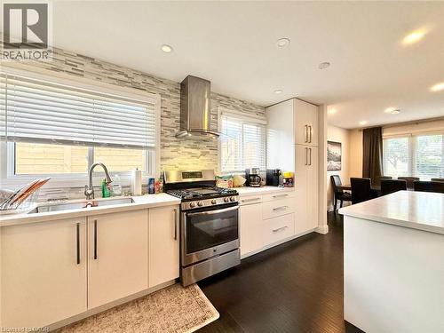 Modern kitchen featuring a stainless steel gas range, coordinating range hood, and crisp white cabinetry - 3135 Palmer Drive, Burlington, ON 