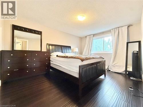 Bedroom with dark wood-finish flooring, a large window, light-toned walls, and ceiling-mounted lighting - 3135 Palmer Drive, Burlington, ON 