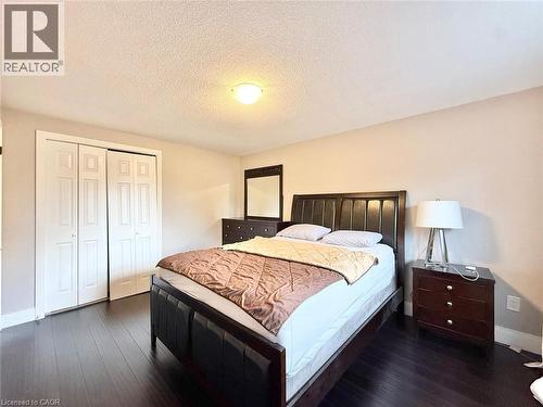 Bedroom featuring dark wood-finish flooring, light neutral-toned walls, and a white textured ceiling - 3135 Palmer Drive, Burlington, ON 