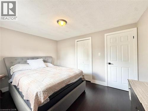 Bedroom featuring dark wood-finish flooring, light neutral wall paint, and white trim - 3135 Palmer Drive, Burlington, ON 