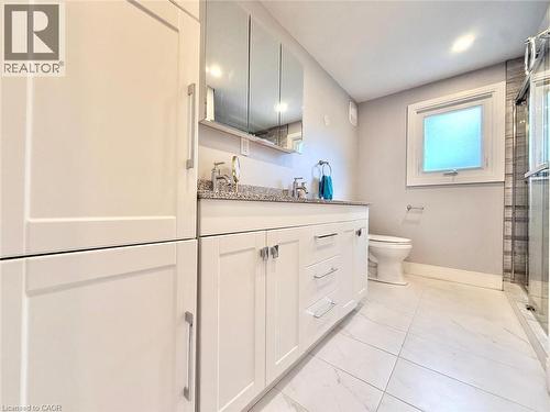 Bathroom featuring a double vanity with stone countertops, white shaker cabinetry, and brushed nickel hardware - 3135 Palmer Drive, Burlington, ON 