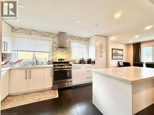 Contemporary kitchen featuring dark wood-finish flooring, white cabinetry, and a large island with a light-toned countertop - 3135 Palmer Drive, Burlington, ON 