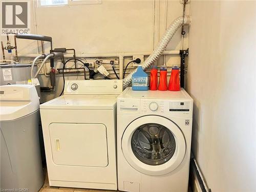 Dedicated laundry area featuring a white front-loading washing machine, a white top-loading dryer, and a water softener system - 110 Peppler Street, Waterloo, ON 