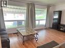 Bright living area featuring expansive windows, wood-finish flooring, a built-in display cabinet, and crown molding - 110 Peppler Street, Waterloo, ON 