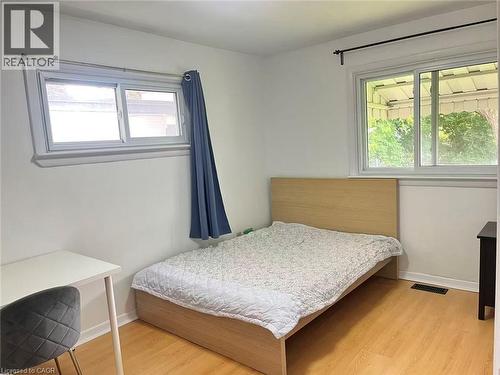 Room featuring light wood-finish flooring, white painted walls, and two multi-pane windows with white trim - 110 Peppler Street, Waterloo, ON 