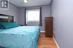 Well-lit room featuring wood-finish flooring and light gray walls - 