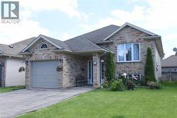 Brick exterior featuring a gabled roofline and an arched window accent above the garage - 