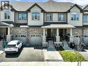 Townhome exterior featuring light-toned siding and a prominent brick facade - 76 Grassbourne Avenue, Kitchener, ON 