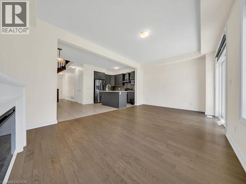 Spacious room featuring wood-finish flooring, a built-in fireplace, and abundant natural light from a large window - 76 Grassbourne Avenue, Kitchener, ON 