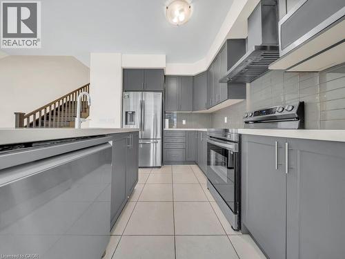 Modern kitchen featuring gray cabinetry, stainless steel appliances, and light tile flooring - 76 Grassbourne Avenue, Kitchener, ON 