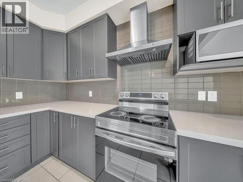 Contemporary kitchen featuring gray shaker-style cabinetry, light-toned countertops, a stainless steel range with a matching range hood, and a built-in microwave - 76 Grassbourne Avenue, Kitchener, ON 