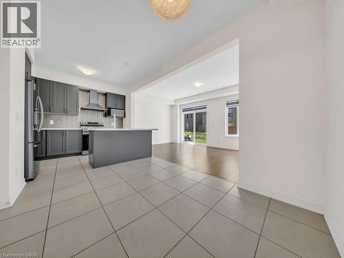 Modern kitchen featuring dark cabinetry, stainless steel appliances, a center island, and tiled flooring - 76 Grassbourne Avenue, Kitchener, ON 