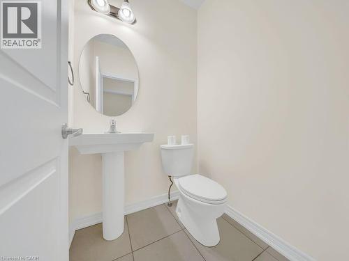 Pedestal sink with an oval mirror, overhead vanity lighting, and ceramic tile flooring - 76 Grassbourne Avenue, Kitchener, ON 