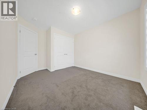 Spacious room featuring neutral-toned walls, plush gray carpeting, and white trim - 76 Grassbourne Avenue, Kitchener, ON 
