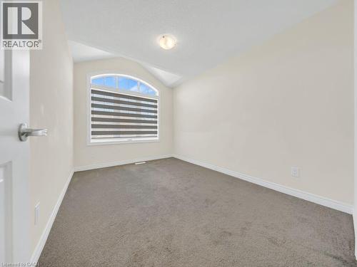 Room featuring a large arched window with horizontal blinds, neutral wall paint, and gray carpet flooring - 76 Grassbourne Avenue, Kitchener, ON 