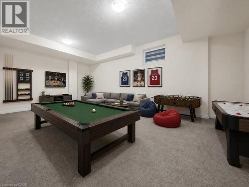 Spacious recreation room featuring neutral carpeting, recessed lighting, and a window with horizontal blinds - 76 Grassbourne Avenue, Kitchener, ON 