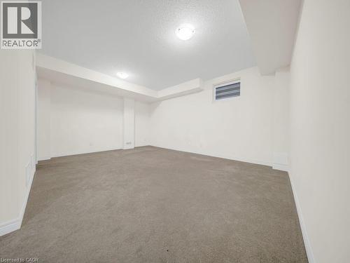Spacious room with light-toned wall-to-wall carpeting and neutral white walls - 76 Grassbourne Avenue, Kitchener, ON 