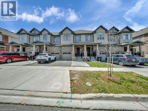 Contemporary townhome exterior featuring light-colored siding, stone accents, and multiple gabled rooflines - 76 Grassbourne Avenue, Kitchener, ON 